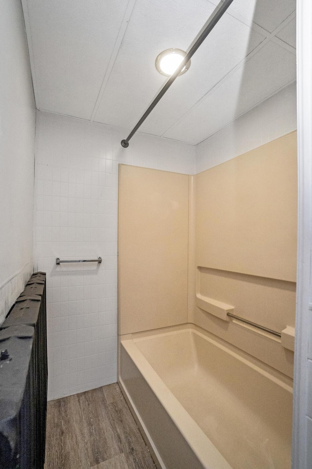 full bath featuring wood finished floors, tile walls, and shower / bath combination