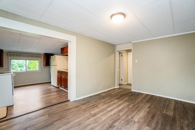 unfurnished room featuring a drop ceiling, wood finished floors, and baseboards
