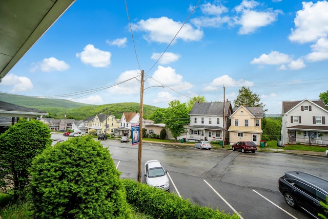 view of asphalt road with a residential view, street lighting, sidewalks, and curbs