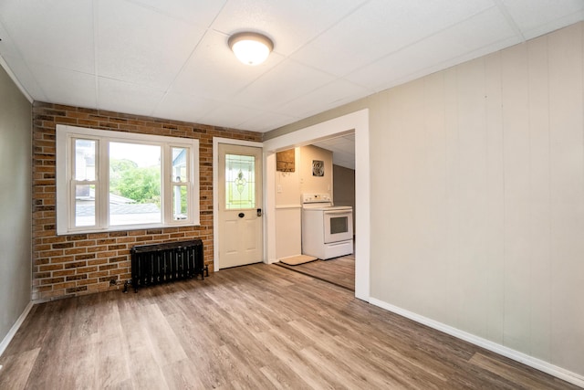 unfurnished living room featuring radiator heating unit, wood finished floors, and baseboards