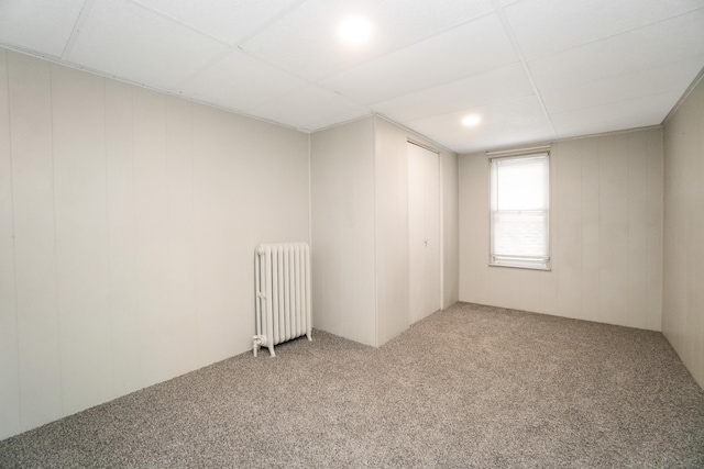 unfurnished room with radiator and light colored carpet