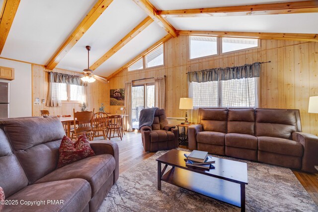 living room featuring hardwood / wood-style flooring, beam ceiling, high vaulted ceiling, and wood walls