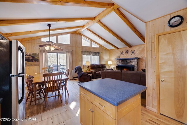 kitchen with lofted ceiling with beams, fridge, wooden walls, and light brown cabinets