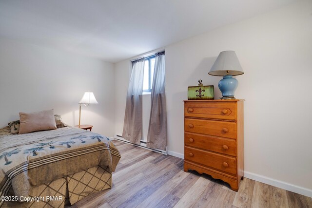 bedroom featuring a baseboard heating unit and light hardwood / wood-style floors