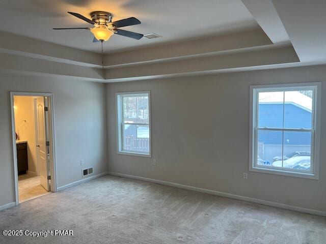 unfurnished room featuring ceiling fan, light colored carpet, and a tray ceiling