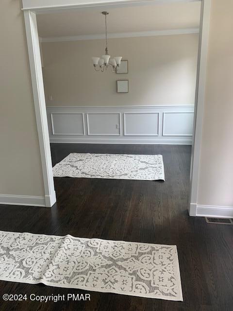 unfurnished dining area featuring a notable chandelier and dark hardwood / wood-style floors