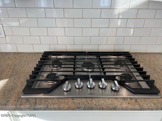 interior details with decorative backsplash and stainless steel gas cooktop