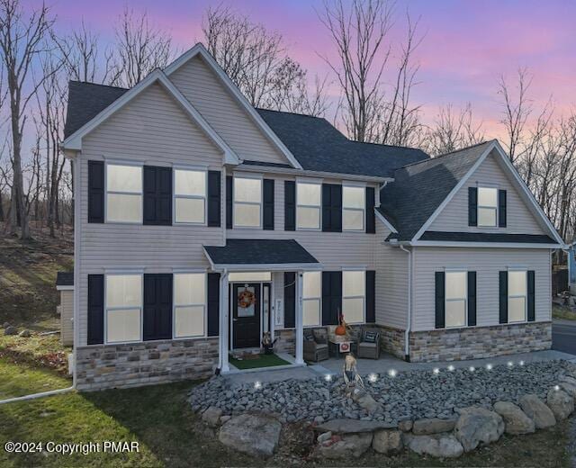 view of front of house with stone siding and roof with shingles