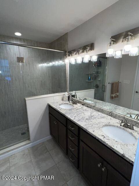 bathroom with an enclosed shower, vanity, and tile patterned floors