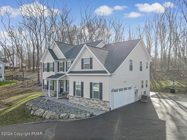 view of front of property featuring a porch, a garage, and central air condition unit