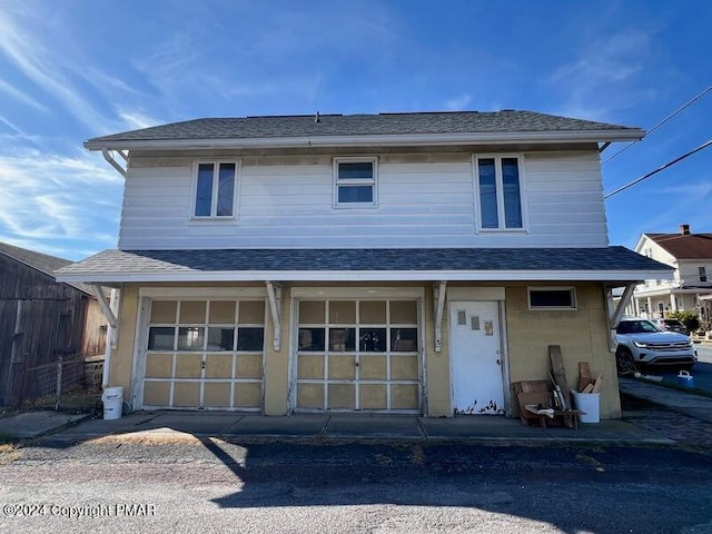 view of front of property featuring an attached garage and roof with shingles