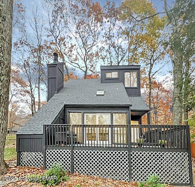 rear view of house featuring roof with shingles and a deck