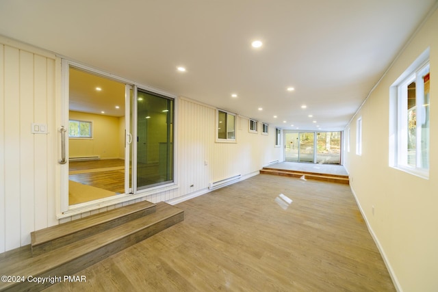 unfurnished room with baseboards, baseboard heating, light wood-type flooring, a baseboard heating unit, and recessed lighting