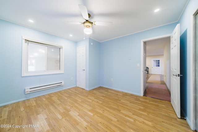 unfurnished bedroom with a baseboard heating unit, light wood-type flooring, crown molding, and baseboards