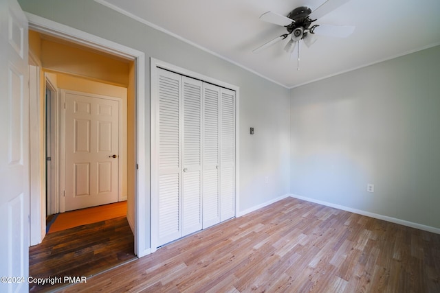 unfurnished bedroom with baseboards, ornamental molding, a closet, and wood finished floors