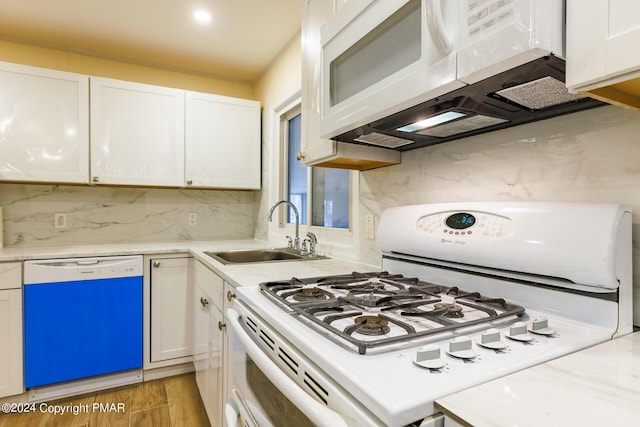 kitchen featuring light wood-style flooring, white appliances, a sink, white cabinetry, and light countertops