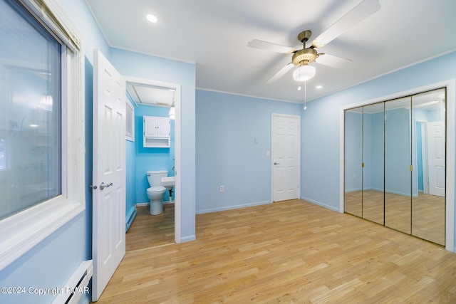 bedroom featuring light wood-style floors, a baseboard heating unit, crown molding, and baseboards