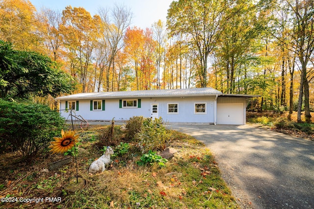 single story home featuring an attached garage, aphalt driveway, and metal roof