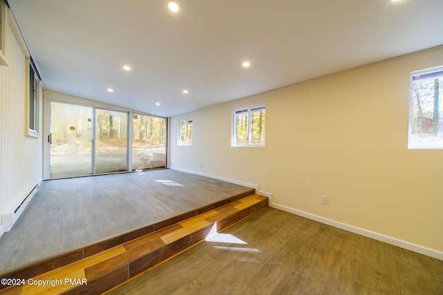 interior space with a healthy amount of sunlight, vaulted ceiling, wood finished floors, and recessed lighting