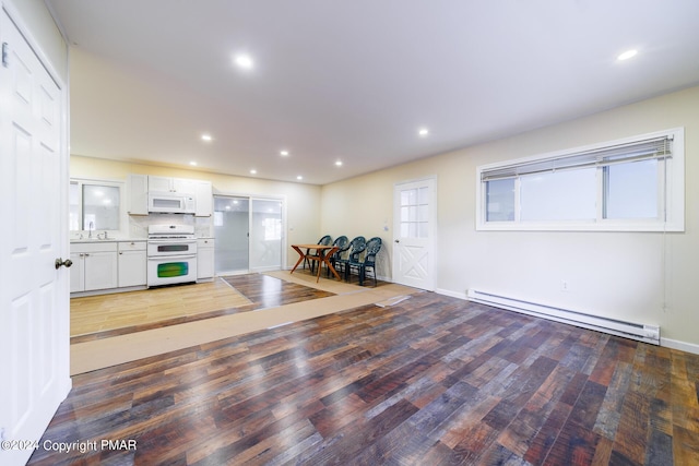 interior space with light wood-type flooring, baseboards, baseboard heating, and recessed lighting