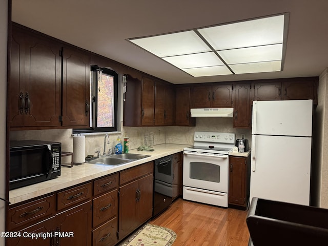 kitchen with light countertops, dark brown cabinetry, a sink, under cabinet range hood, and black appliances