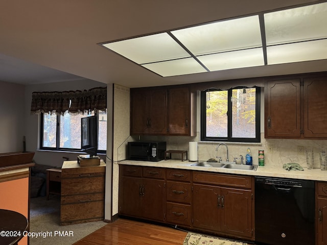 kitchen with light wood-style flooring, a sink, light countertops, black appliances, and backsplash