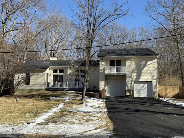 view of front of property with a garage, driveway, a balcony, and fence