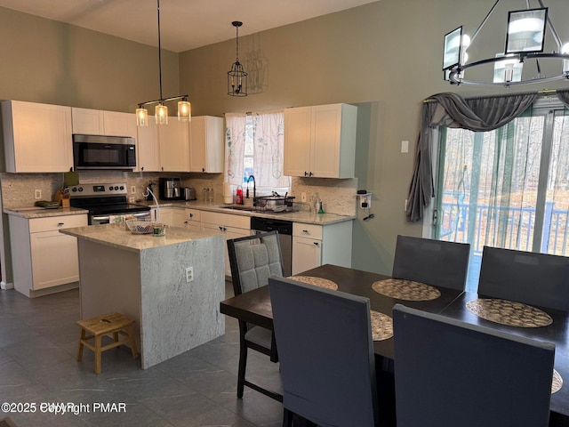 kitchen featuring white cabinetry, stainless steel appliances, a sink, and a center island