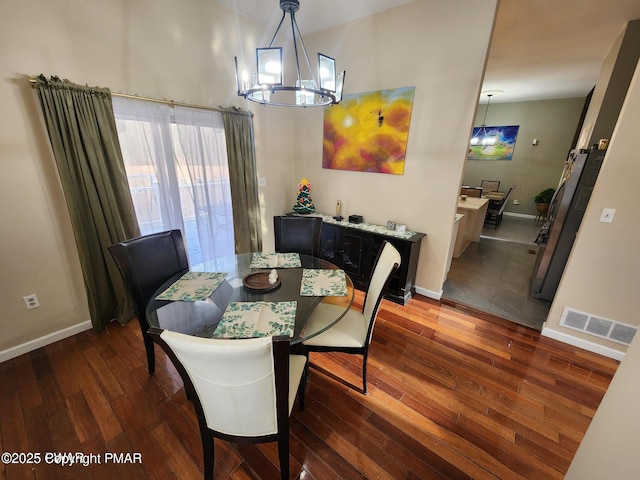 dining area featuring a chandelier, dark wood-type flooring, visible vents, and baseboards