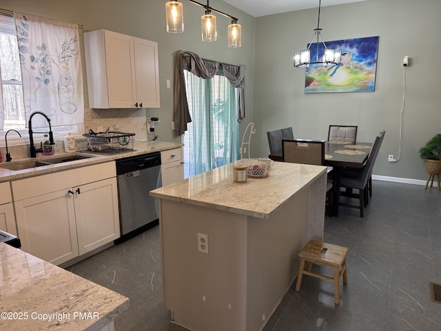 kitchen featuring light stone counters, backsplash, stainless steel dishwasher, white cabinetry, and a sink