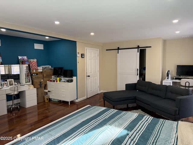 bedroom with baseboards, a barn door, wood finished floors, and recessed lighting