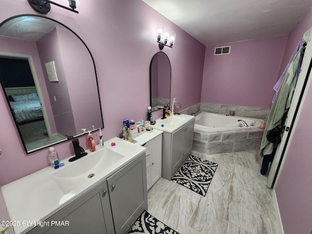 ensuite bathroom featuring two vanities, visible vents, a sink, and a garden tub