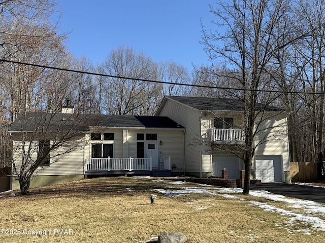 split level home featuring aphalt driveway, a chimney, a balcony, and a garage