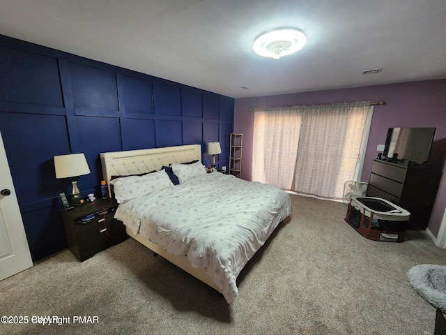 bedroom featuring light carpet, visible vents, and a decorative wall