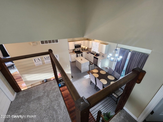 carpeted dining room featuring baseboards, visible vents, a towering ceiling, a chandelier, and a sink