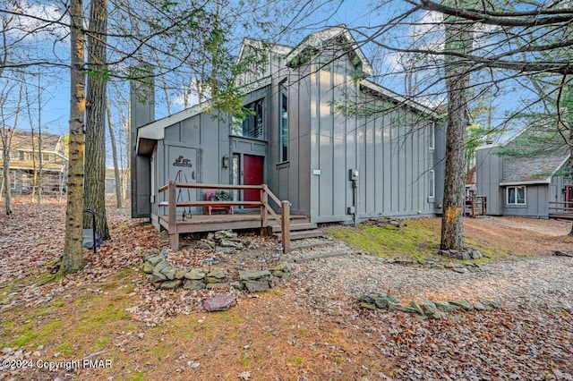 rear view of property featuring a chimney and board and batten siding