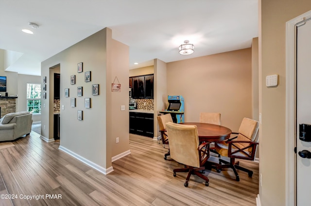 dining room featuring light wood-style floors, recessed lighting, a fireplace, and baseboards