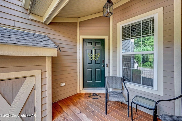 entrance to property with covered porch and roof with shingles