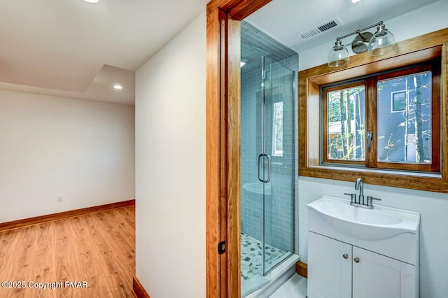 full bathroom with a stall shower, baseboards, visible vents, wood finished floors, and vanity