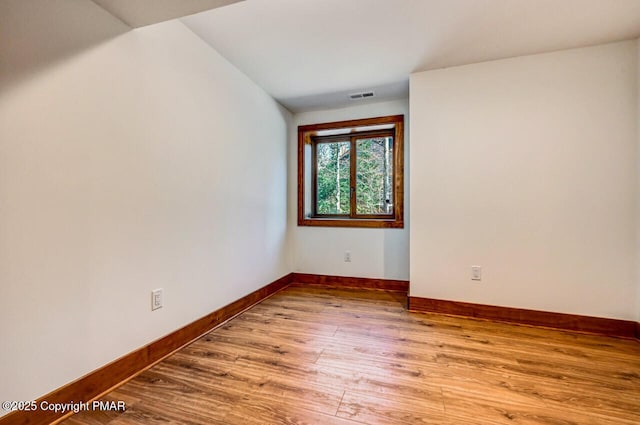 unfurnished room with baseboards, visible vents, and wood finished floors