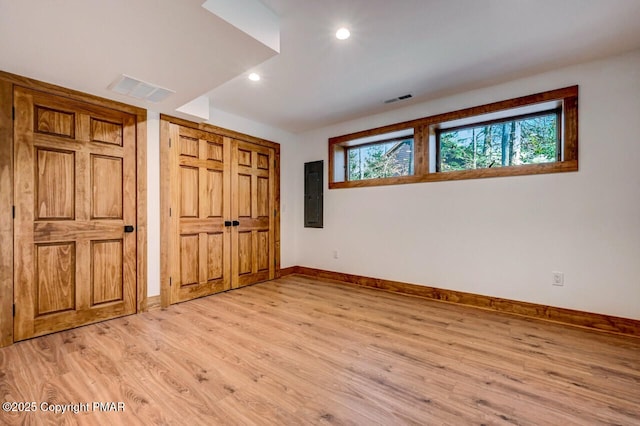 unfurnished bedroom featuring light wood finished floors, baseboards, electric panel, and visible vents