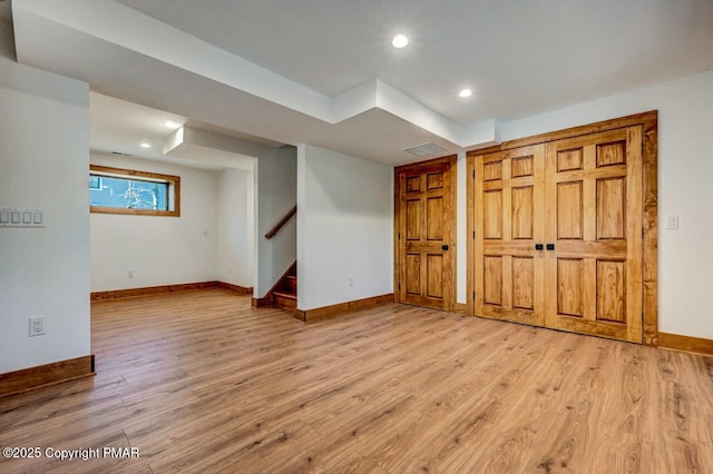 basement featuring stairway, visible vents, light wood-style flooring, and baseboards