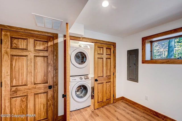 laundry room with light wood finished floors, laundry area, electric panel, visible vents, and stacked washing maching and dryer