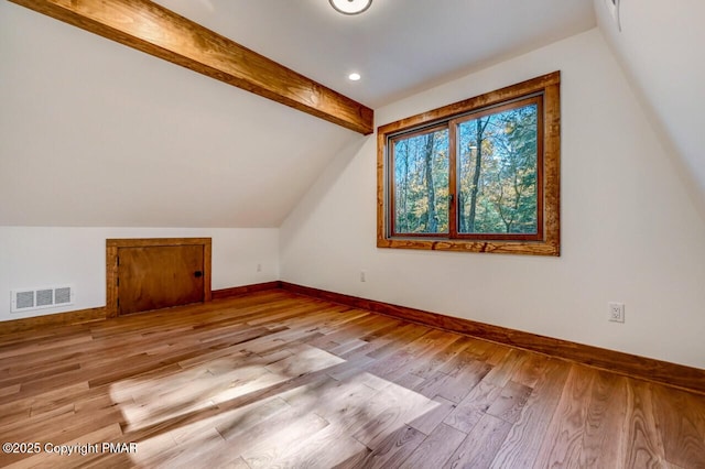 additional living space featuring visible vents, vaulted ceiling with beams, baseboards, and wood finished floors