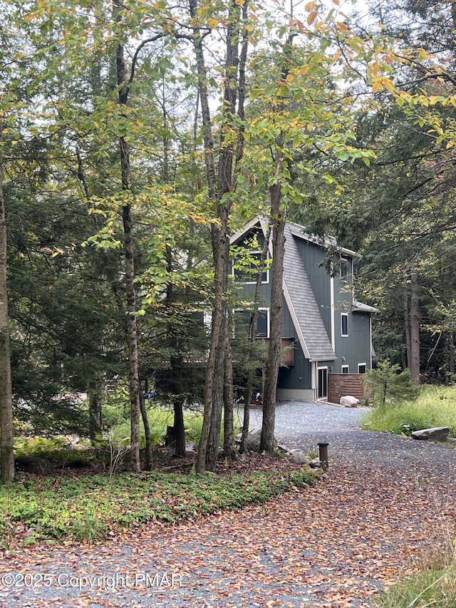 view of front of home featuring a forest view and a shingled roof