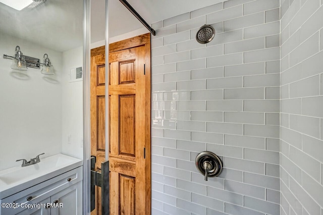 bathroom with a tile shower and vanity