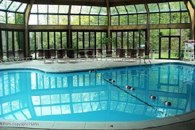 community pool featuring glass enclosure and a patio