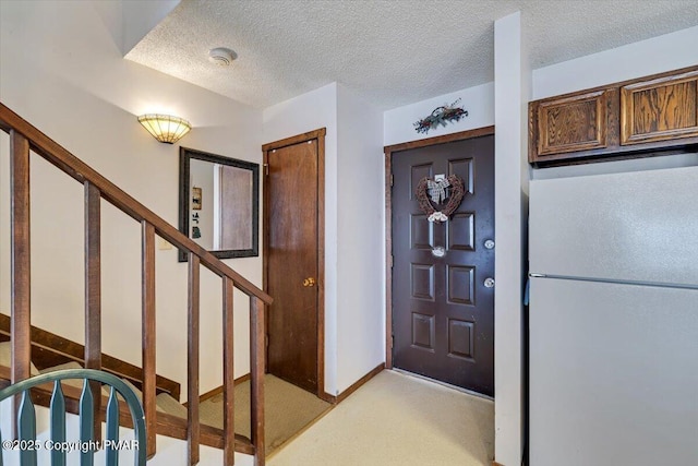 foyer entrance featuring a textured ceiling, baseboards, and stairs