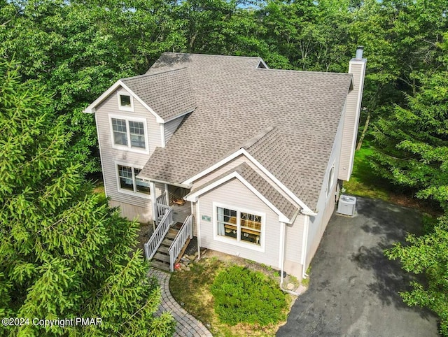 view of front of property featuring stairs, roof with shingles, and a chimney