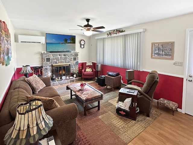 7537 Lake Shore Dr, Pocono Lake, PA 18347 - living area with a wall unit AC, wood finished floors, a ceiling fan, and a stone fireplace